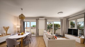 Una sala de estar moderna con comedor, ventanas amplias y un televisor de pantalla plana.