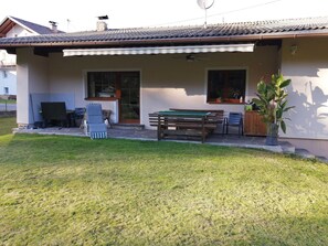Una casa con un porche cubierto, mesa de billar, mobiliario exterior y una planta en maceta.
