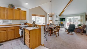 A spacious kitchen with wooden cabinets, a central island, and a dining area with a chandelier.