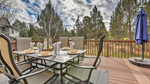 An outdoor deck with a dining table set for four, surrounded by chairs.