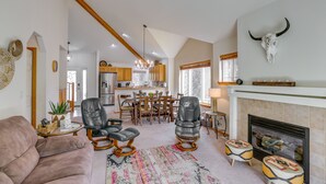 A spacious living room with a fireplace, leather chairs, and a dining area in the background.