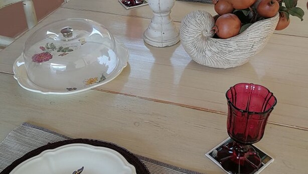 A dining table set with various dishes, a decorative bowl, and a red glass vase. - Glyfada's Cosy Apartments (Glyfada)