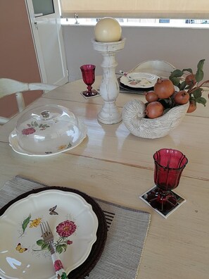 Une table à manger dressée avec différents plats, un bol décoratif et un vase en verre rouge.
