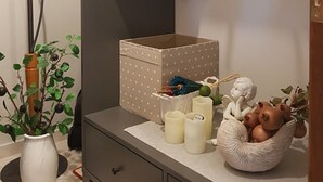 A modern bathroom with a dark vanity, a white vase with a plant, a white polka-dotted box, and a decorative angel figurine. - Glyfada's Cosy Apartments (Glyfada)