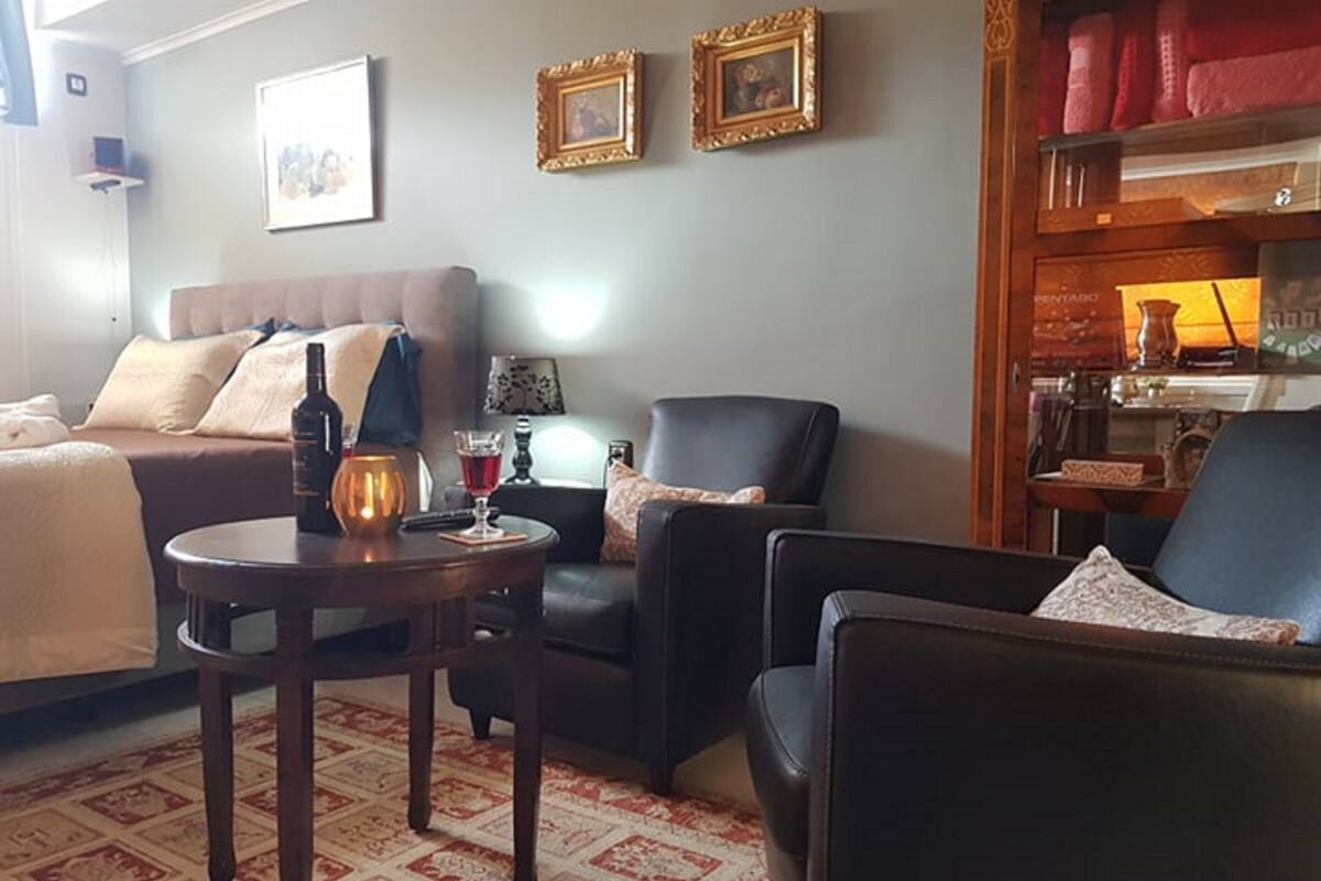 A cozy living room with a sofa, two armchairs, a coffee table, and a patterned carpet.
