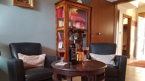 A living room with two black leather sofas, a wooden coffee table, and a glass cabinet with various items. - Glyfada's Cosy Apartments (Glyfada)