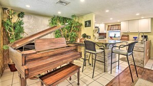 Een keuken met een piano, een eethoek met stoelen en een keukeneiland.