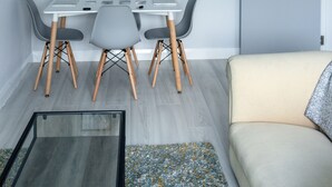 Un salon moderne avec un coin repas, comprenant un canapé blanc, une table à manger avec quatre chaises et un luminaire suspendu au plafond.