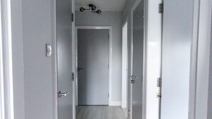 Un couloir avec des portes blanches et un parquet en bois clair.