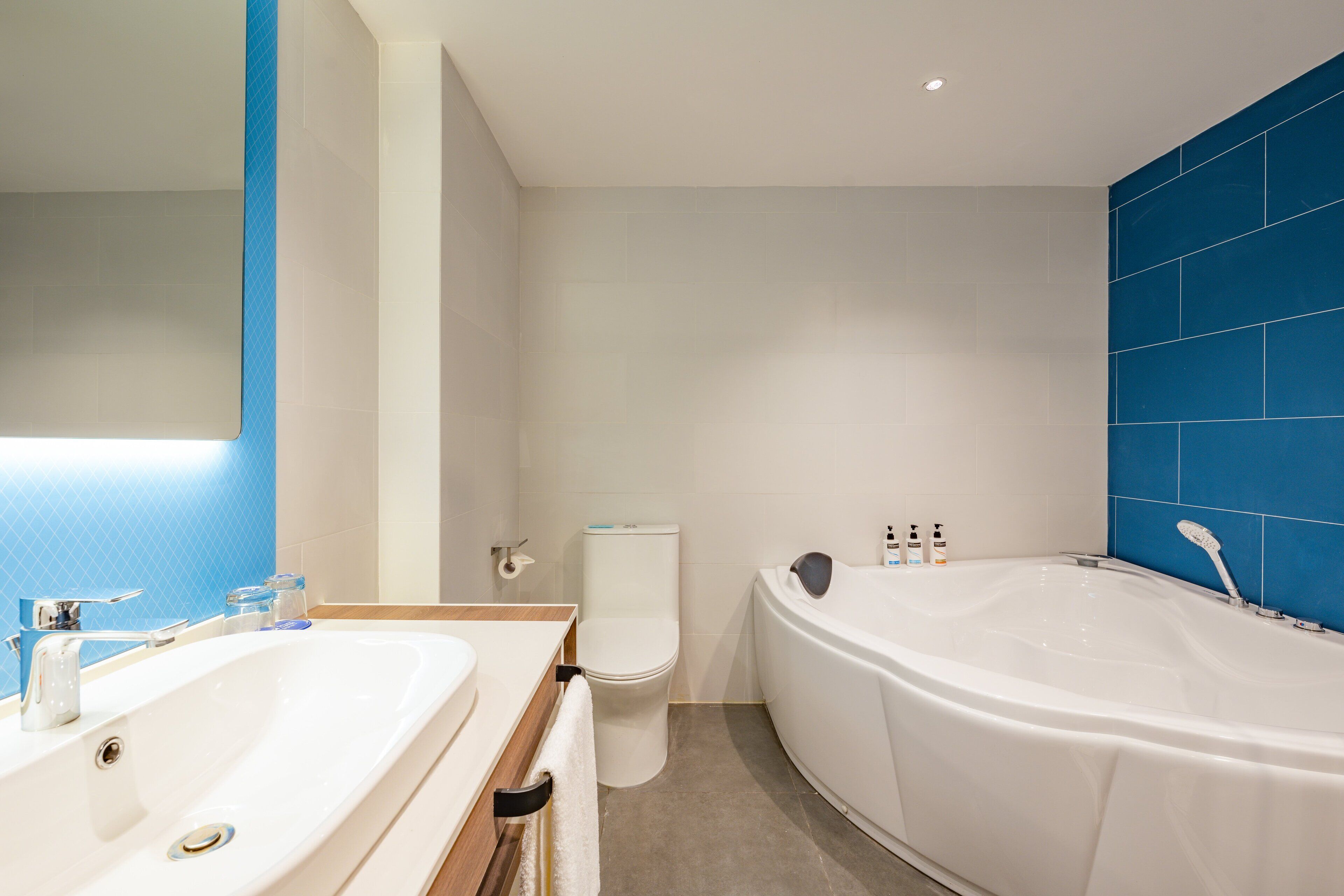 Un baño moderno con una bañera grande, dos lavamanos y un inodoro.