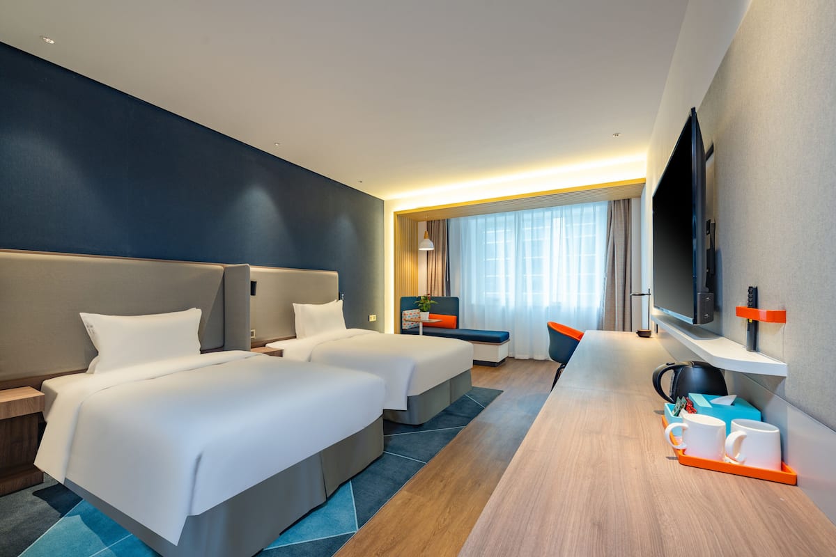 A hotel room with two beds, a desk, a TV, and a coffee tray.