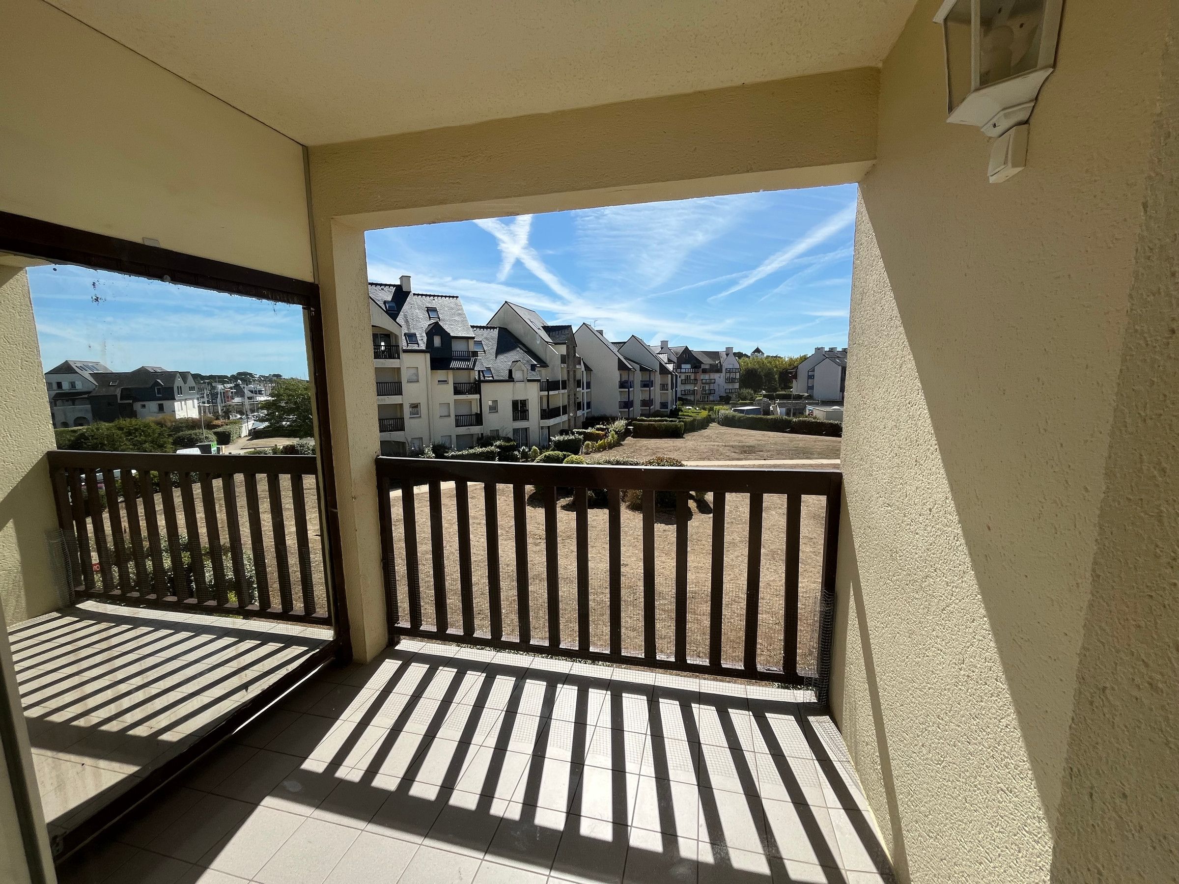 A balcony with a view of residential buildings and a clear sky.