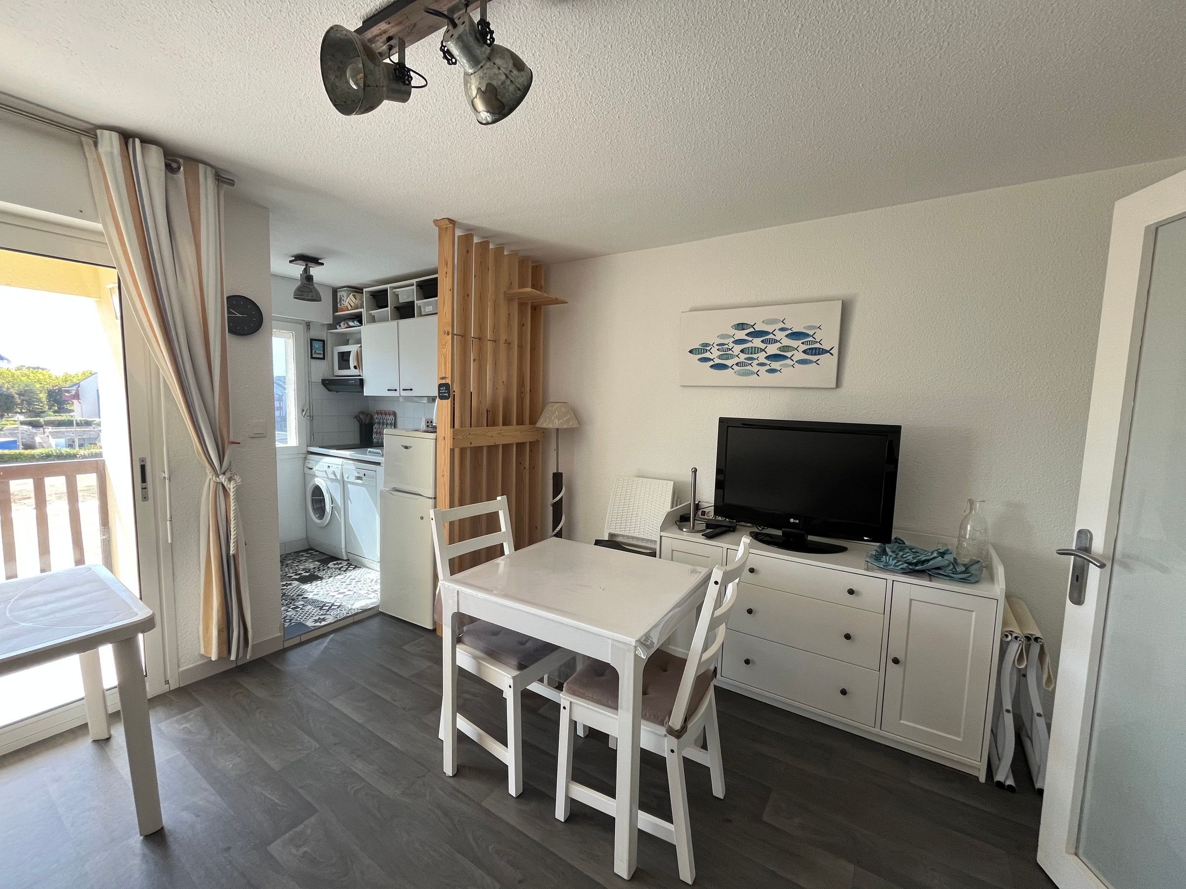 A compact living space with a dining area, kitchenette, and a television.