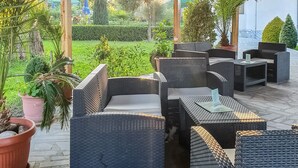 Eine Terrasss mit Korbmöbeln, Topfpflanzen und einer Holzbeschichtung.