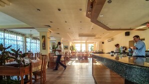 Ein geräumiges Restaurant mit Holzböden, einer zentralen Bar und einem Essbereich mit Tischen und Stühlen.