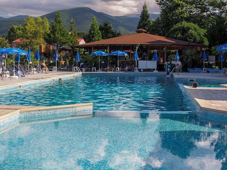 Alberca al aire libre, sombrillas en la alberca y camastros