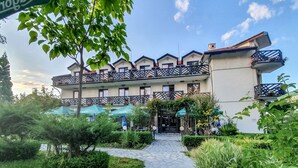 Ein Hotel mit einem Kiesweg zum Eingang, umgeben von Grünflächen und Sitzbereichen im Freien.