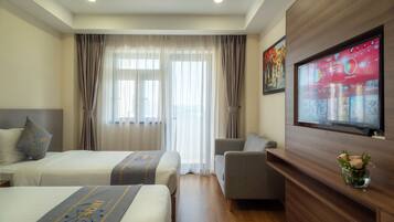 A hotel room with two beds, a sofa, a TV, and a wooden cabinet.