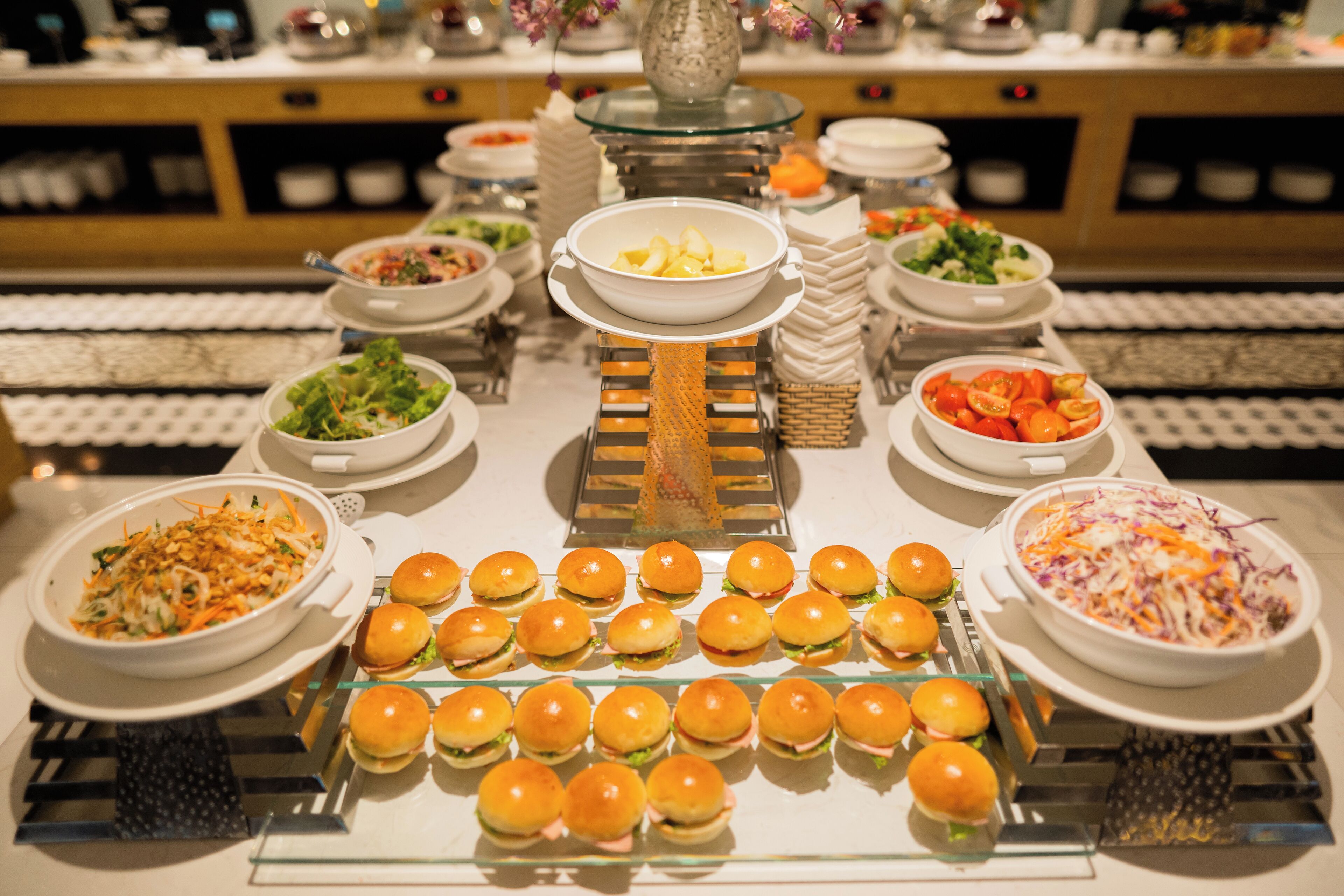 Un buffet con diversi cibi, tra cui insalate, insalata di cavolo e panini.