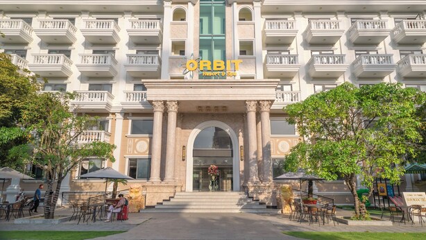 Un hotel con una entrada imponente, varios balcones y zonas de estar al aire libre.