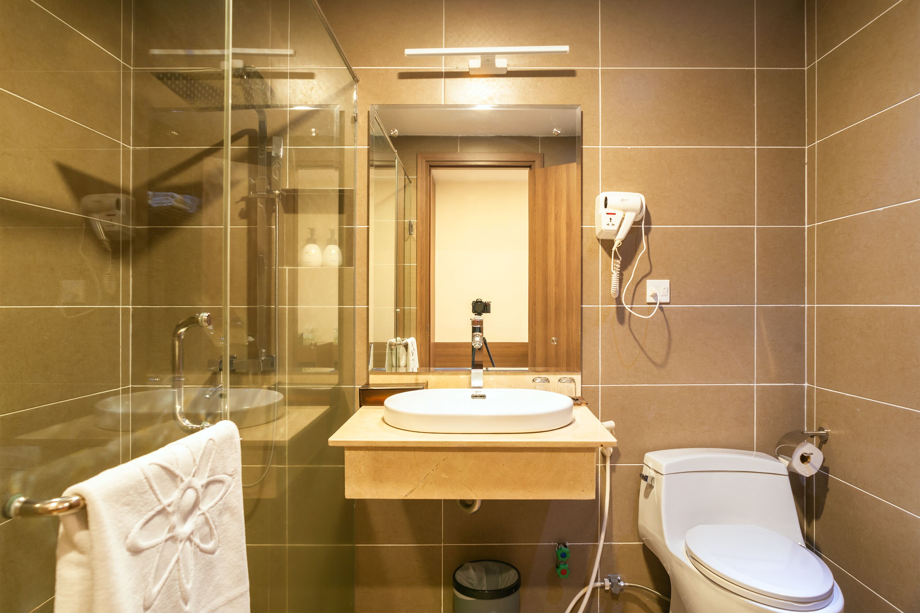 Un bagno moderno con doccia vetro, lavandino con specchio sopra e servizi igienici.