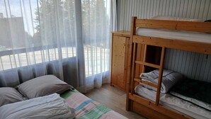 A room with a bunk bed, a wooden cabinet, and a large window with sheer curtains. - Beautiful 2-room apartment at the foot of the slopes in Chamrousse (Chamrousse)