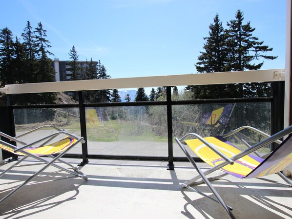 Enjoy breathtaking views of the mountains from this balcony with two lounge chairs.