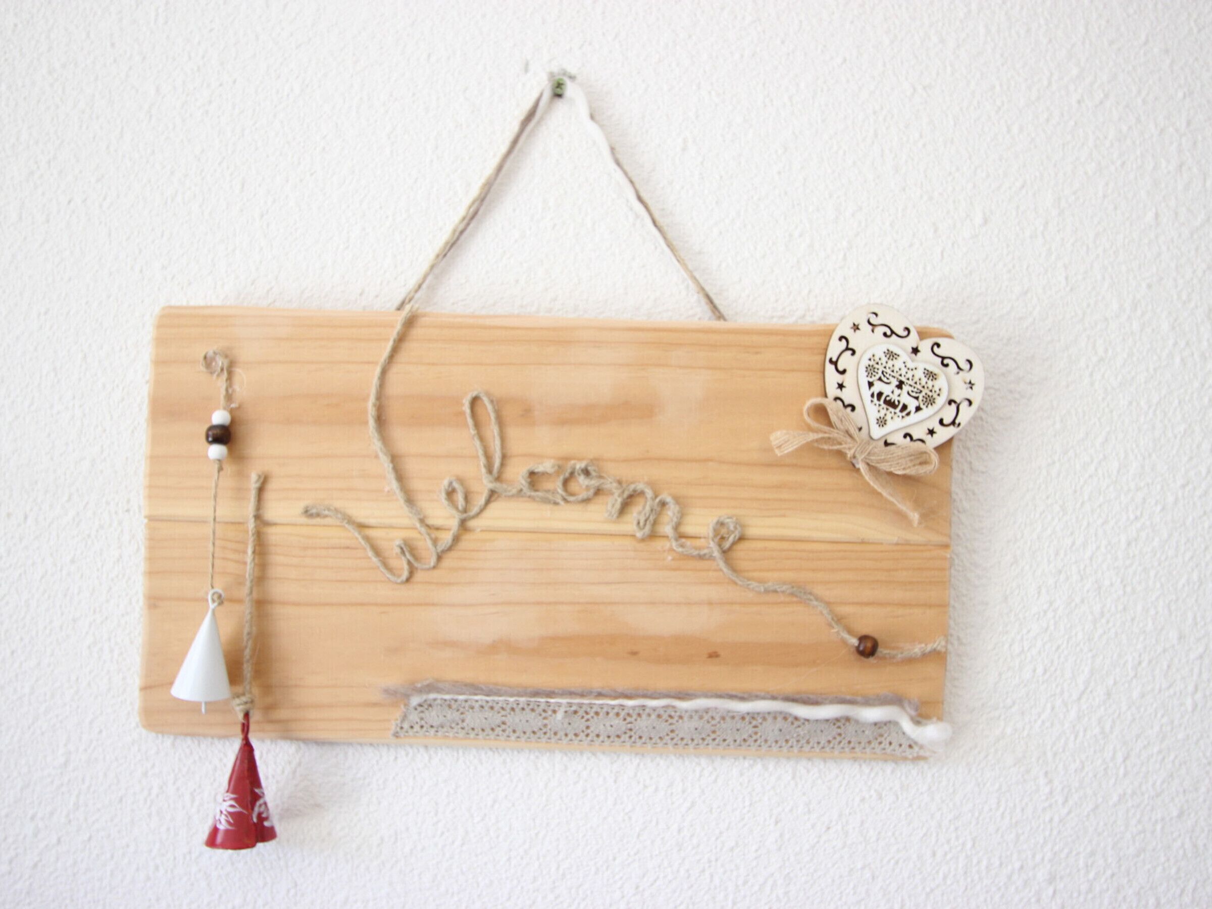 Un letrero de madera con un adorno en forma de corazón y encaje.