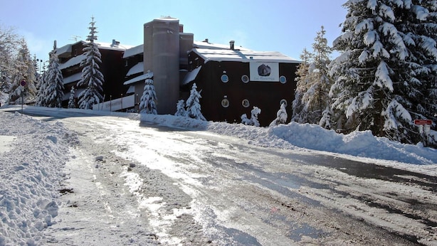 Un edifici amb un rètol que diu "Los Mucientes" envoltat d'arbres coberts de neu i un paisatge nevós.