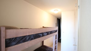 Un llit superposat en una habitació amb una porta i una làmpada al sostre.