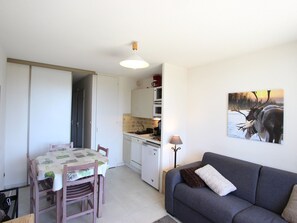 Cozy living space with a kitchenette, dining table, and sofa, featuring a microwave, coffee maker, and sink.