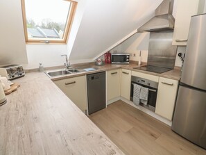 A modern kitchen with a dishwasher, microwave, stove, and refrigerator. - Upper Deck (Truro)