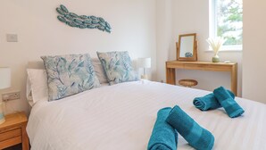 A hotel room with a bed, a nightstand, a desk with a mirror, and a window. - Upper Deck (Truro)