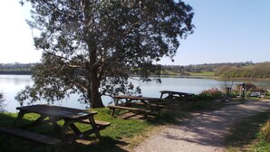 A lakeside picnic area with wooden benches and a walking path. - Upper Deck (Truro)