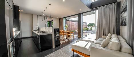 A modern kitchen with a dining area and a living room with a sofa.
