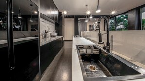 Una cocina moderna con una isla central, muebles negros y un amplio ventanal que ofrece vistas al exterior.
