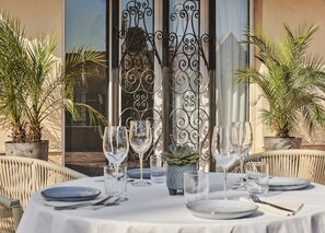 Mesa preparada para comer con vista a un edificio y palmeras.