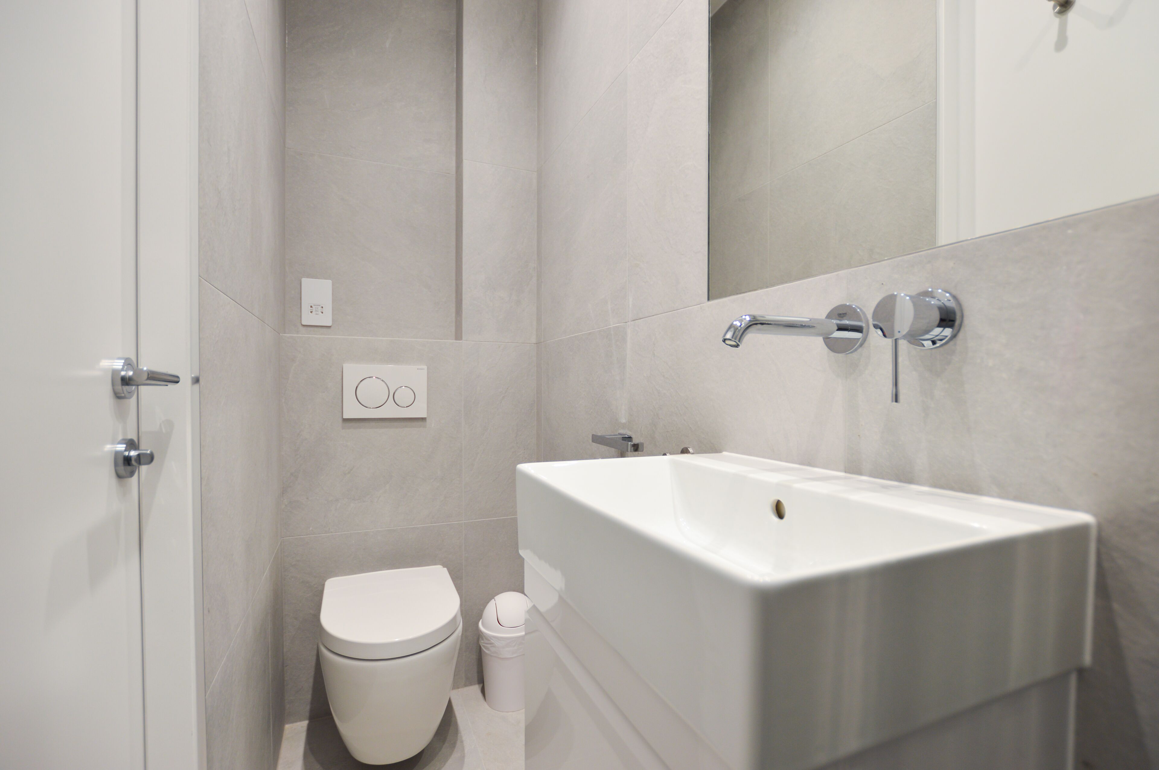 A modern bathroom with a toilet, sink, and shower.