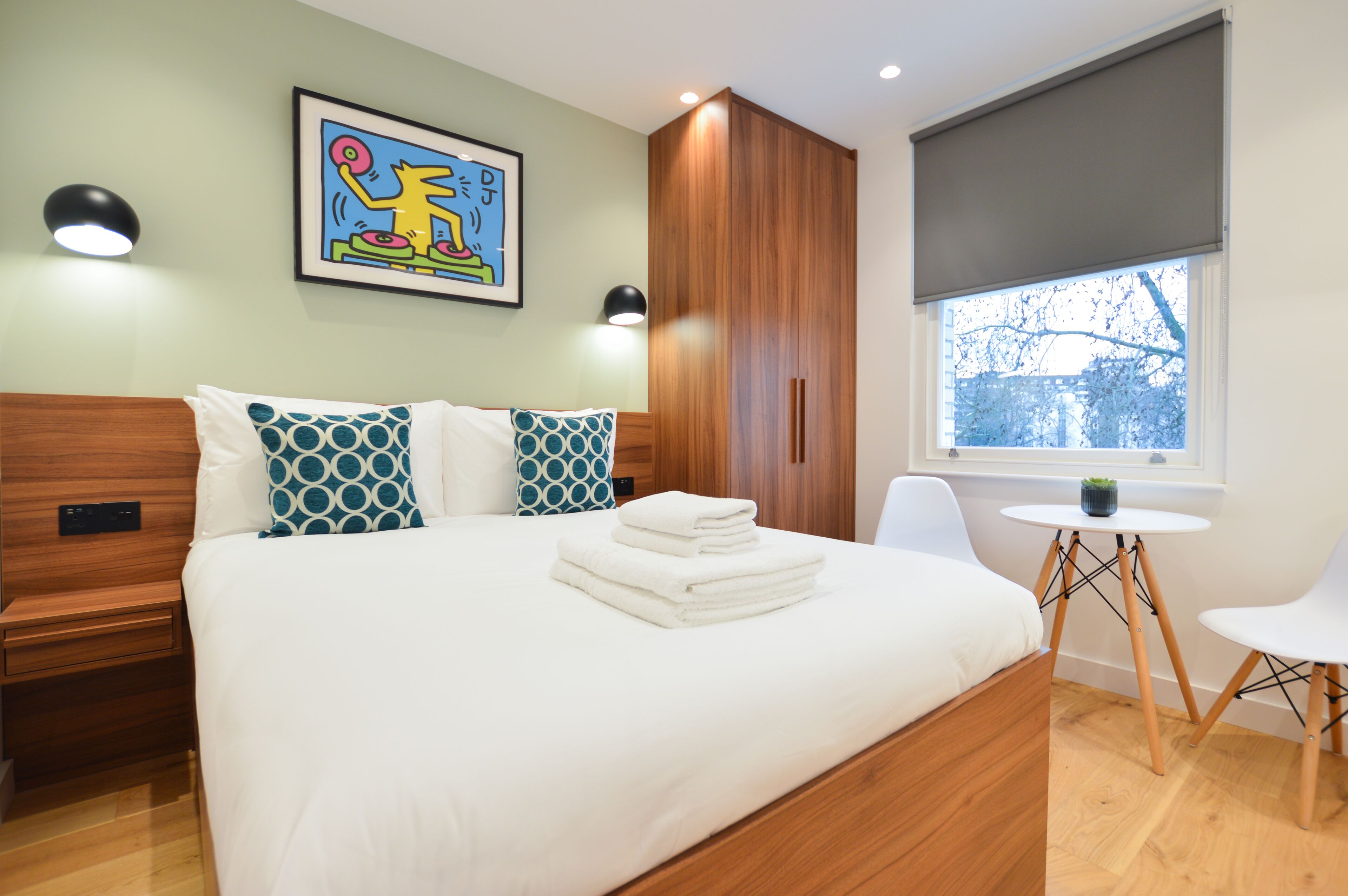 Une chambre d’hôtel moderne avec un grand lit, une petite table et une fenêtre donnant sur un beau paysage.