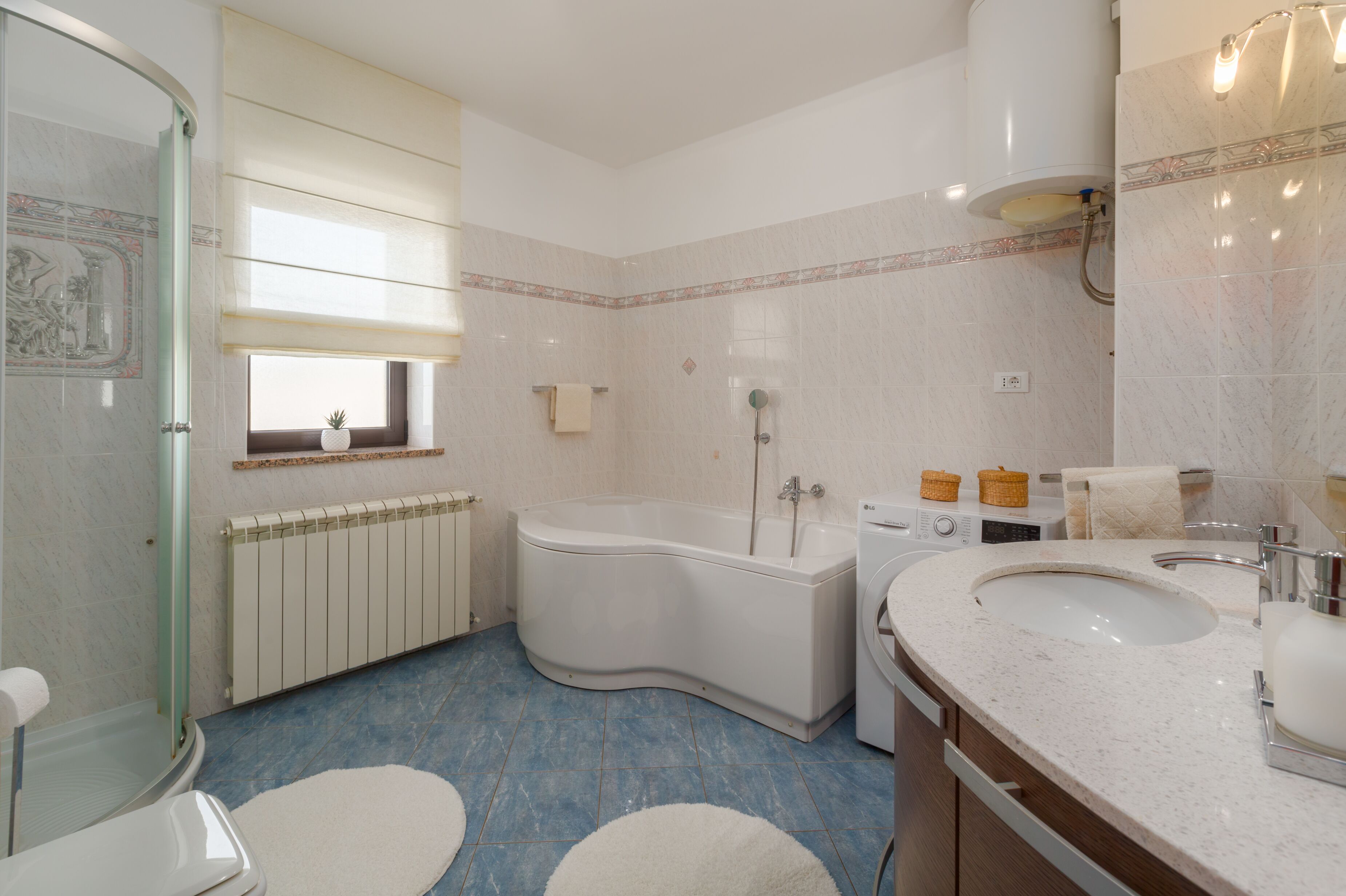 Ein Badezimmer mit Badewanne, Waschbecken, Toilette und einem Fenster.