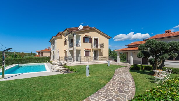 Ein zweistöckiges Haus mit Swimmingpool, einem Kiesweg und einem gepflegten Rasen.