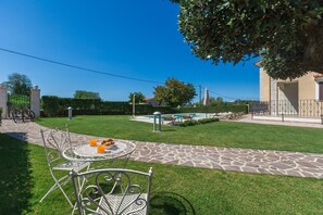 A patio with a table and chairs, a stone pathway, and a swimming pool in the background. - Pool, sun loungers, well-kept garden,family-friendly, barbecue, garden furniture (Vižinada)