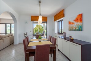 A dining area with a wooden table, red chairs, a potted plant, and a view of the outdoors. - Pool, sun loungers, well-kept garden,family-friendly, barbecue, garden furniture (Vižinada)