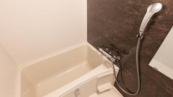 A bathroom with a bathtub, a shower, and a marble wall.