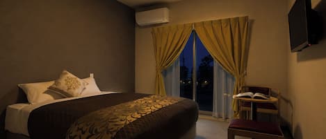 A hotel room with a bed, a desk, and a chair.
