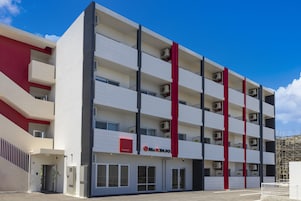 Egy modern, többemeletes szálloda, vörös és fehér színű homlokzattal, számos eréllyel és légkondicionáló berendezésekkel.