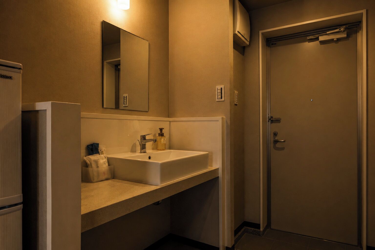 A bathroom with a sink, mirror, and a door.