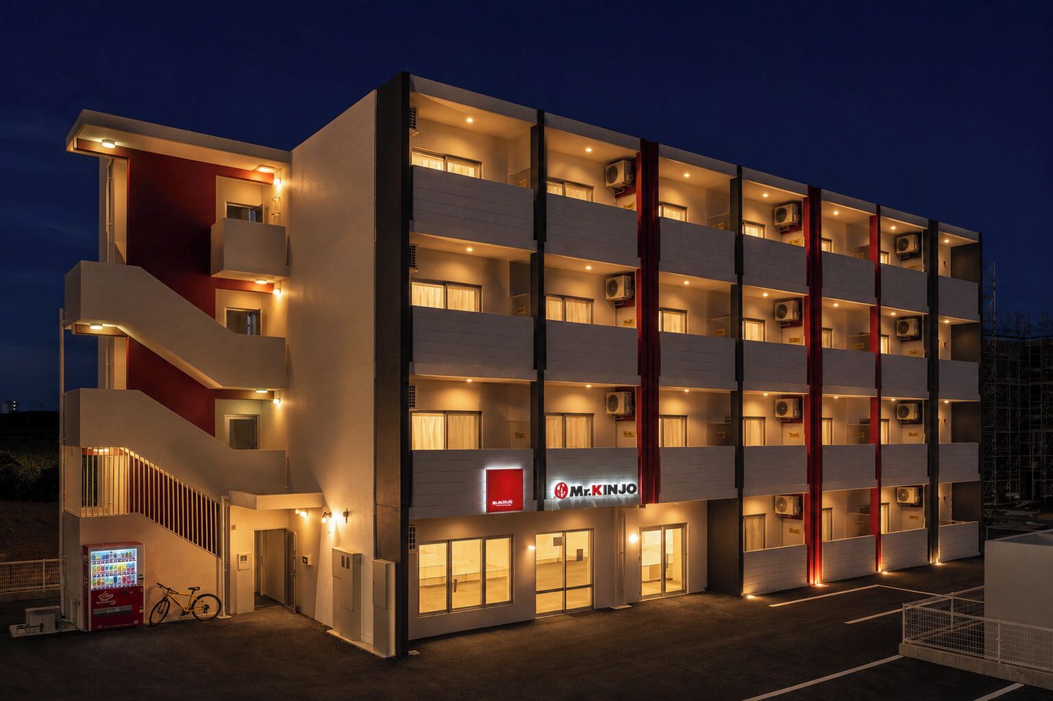 A multi-story hotel with a modern design, featuring balconies, air conditioning units, and a prominent signage for 'Mr. Kinjo'.