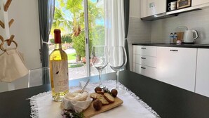 Une cuisine moderne avec un coin repas, comprenant une table dressée avec des verres à vin, une bouteille de vin et une planche à fromages.