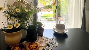 Une table à manger ornée d’un arrangement floral, une tasse de café et une assiette de pâtisseries.